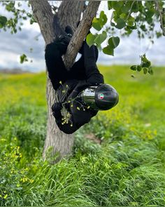 a person in a black suit is hanging from a tree with a helmet on his head