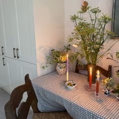 a dining room table with three candles on it and some flowers in the vases