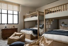 a bedroom with bunk beds and two chairs in it, next to a large window