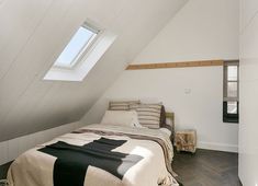 a bed sitting under a window in a bedroom next to a wooden floor and white walls