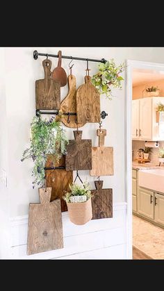 a kitchen wall with cutting boards hanging from it's sides and potted plants on the hooks