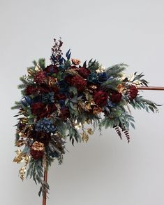 an arrangement of flowers and greenery on a stick