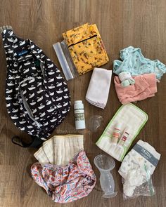 the contents of a diaper bag laid out on a wooden floor next to it