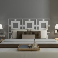 a bed with white headboard and pillows in a bedroom next to two lamps on either side of the bed