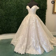 a white wedding dress on display in front of a green wall