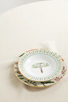 two plates sitting on top of a table covered in white cloth and colorful designs,