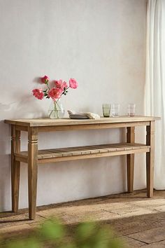 a wooden table with flowers on it in front of a window