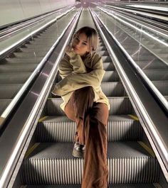 a woman is sitting on an escalator with her legs crossed and looking at the camera