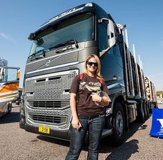 a woman standing in front of a semi truck