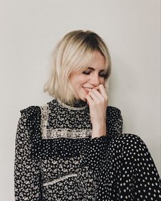 a woman with blonde hair wearing a black and white polka dot dress, posing for the camera