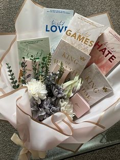 a bouquet of flowers sitting on top of a white paper wrapped in brown ribbon and surrounded by books