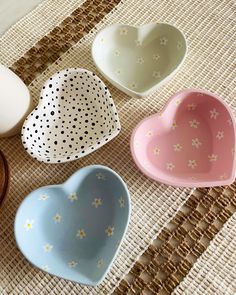 four heart shaped dishes sitting on top of a woven tablecloth next to an egg