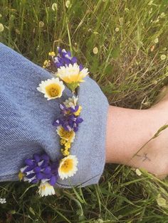 a person's arm with flowers in the grass