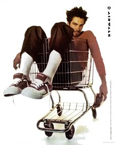 a man sitting in a shopping cart with his feet up on the top of it