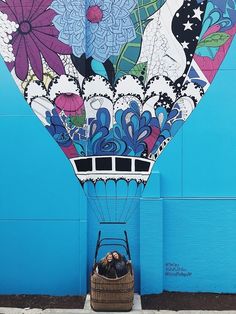 a person sitting in a basket on the ground next to a large hot air balloon