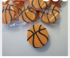 basketball cookies wrapped in plastic wrappers and tied with orange ribbon on white table top