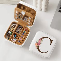 an open jewelry box sitting on top of a white table next to a laptop computer