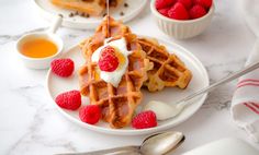 the waffles are topped with whipped cream and raspberries on the plate