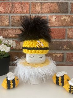 a crocheted doll wearing a yellow and black hat with white fur on it