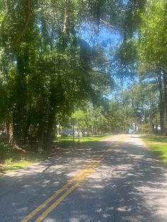 an empty road surrounded by trees and grass