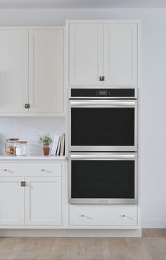 a kitchen with white cabinets and an oven in the center, along with wooden flooring