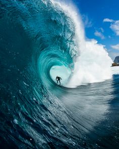 a man riding a wave on top of a surfboard in the ocean under a blue sky