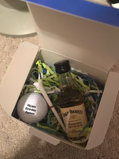 an open box with a golf ball and some liquor