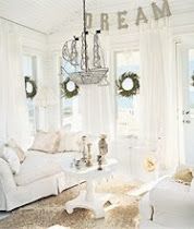 a living room with white furniture and wreaths on the windows sill in front of them