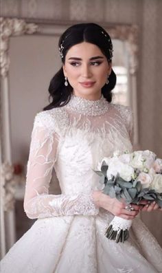 a woman in a wedding dress holding a bouquet of flowers and wearing a tiara