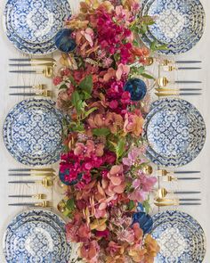 the table is set with blue and white plates, silverware, and flowers on it