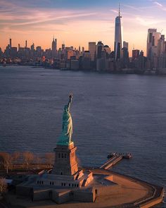 an aerial view of the statue of liberty in new york city, ny at sunset