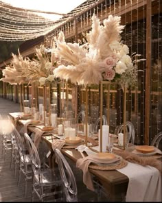 a long table set up with tall vases filled with flowers and candles