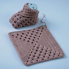 two crocheted items are sitting next to each other on a blue table top