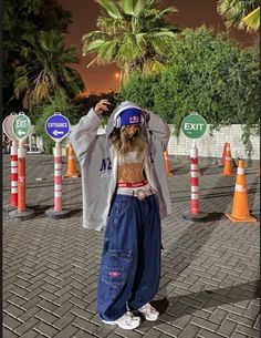 a woman standing in front of orange and white traffic cones with her hands on her head