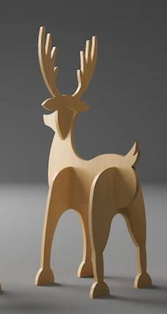 two wooden deer standing next to each other on a gray surface with one looking at the camera