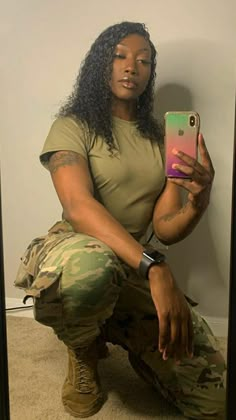 a woman is taking a selfie with her cell phone while wearing camo pants