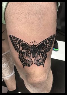 a black and white butterfly tattoo on the right leg, it looks like he is sitting down