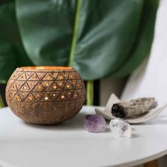 a wooden candle holder sitting on top of a table next to some rocks and a plant