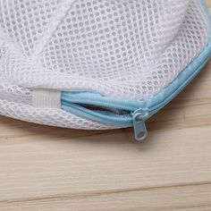 a close up of a white mesh bag on a wooden surface with a blue zipper