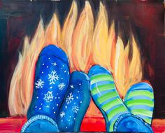 two blue boots sitting in front of a fire with snowflakes on them and one has green striped socks