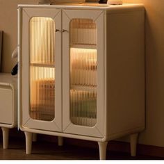 a white cabinet with glass doors in the corner next to a chair and wall lamp