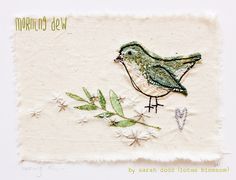 a small embroidered bird sitting on top of a piece of paper with leaves and flowers