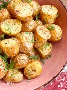 a pink bowl filled with cooked potatoes and garnished with herbs