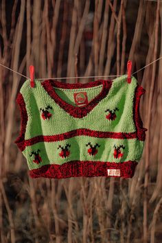 a green sweater hanging on a clothes line in front of some dry grass and trees