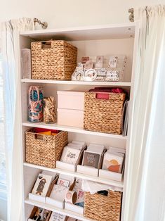 a white book shelf filled with lots of books and wicker baskets next to a window