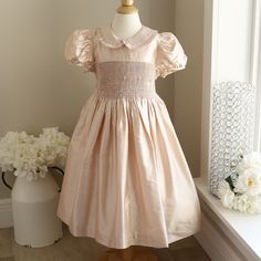 This Girl's Blush Pink Smocked Dress In Size 5 Is Gorgeous!! This Luli & Me Boutique Dress Is Made Of 100% Silk Dupioni With Smocking And Embroidery. The Peter Pan Collar Is Trimmed In A Matching Gathered Ruffle. The Short Puff Sleeves Gather With A Matching Piping For A Smooth Edge. The Smocked Lower Bodice And Waist Is Done In A Beautiful Lattice Accordion Smocking, Accented With Two Shades Of Pink Embroidered Zig-Zag Horizontal Rows. In Addition, Sweet Pink Bullion Rose Buds With Green Leaves Luxury Pink Smocked Dress With Ruffles, Pink Dress With Smocked Bodice For Dress-up, Luxury Pink Smocked Dress, Smocked Flower Girl Dresses, Girl Silk Dress, Bullion Rose, Dupioni Silk Dress, Pink Short-sleeved Dress With Smocked Cuffs, Christmas Dresses