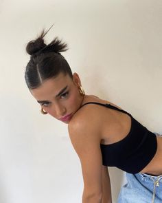 a woman in black shirt and jeans leaning on wall