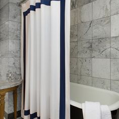 a white bath tub sitting next to a shower curtain in a bathroom with marble walls