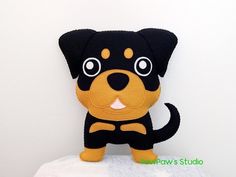 a black and brown dog stuffed animal sitting on top of a white surface with its eyes wide open