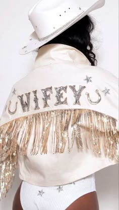 a woman wearing a white cowboy hat and jacket with gold sequins on it